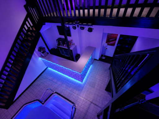Modern interior with purple lighting, stairs, and a reception area.