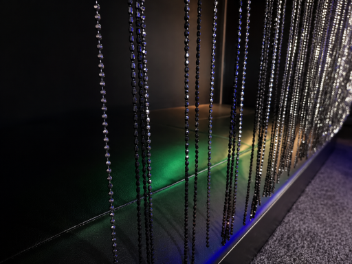 Vertical strands of beads reflecting light, creating a shimmering effect against a dark background.