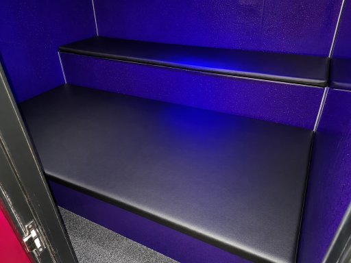 Dark purple booth interior with two long black benches and soft lighting.