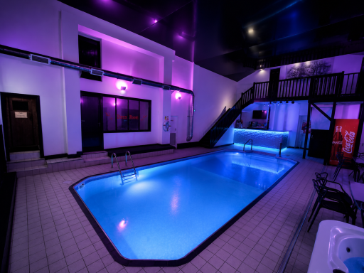 Indoor swimming pool with purple lighting and modern design.