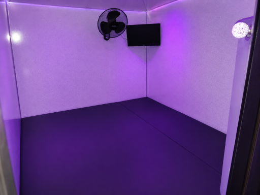 Empty room with purple lighting, a fan, and a wall-mounted TV.