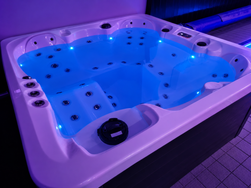 A modern hot tub with blue water and LED lights, featuring multiple seating areas.