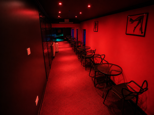 A dimly lit corridor with red walls and tables on either side.