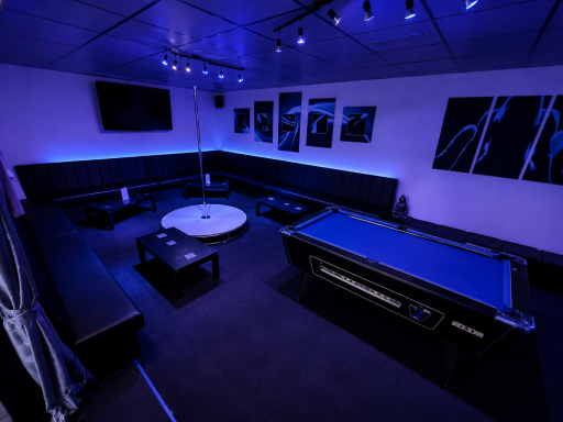 A modern lounge with blue lighting, a pool table, and stylish seating areas.