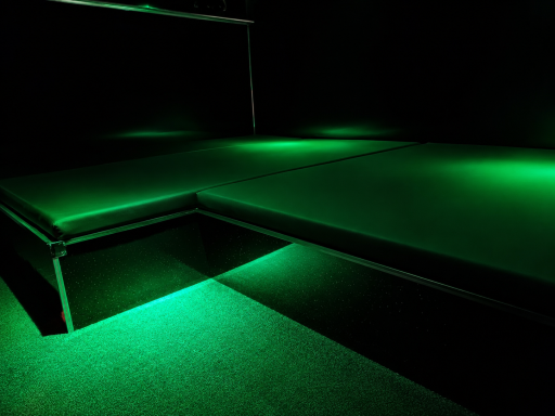 A dark room with a green-lit platform and subtle lighting effects.