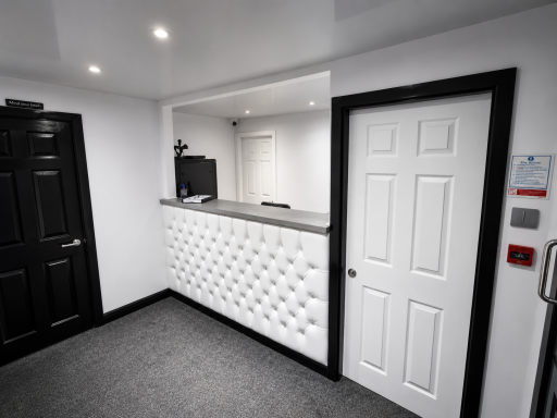 Modern reception area featuring a white desk, black doors, and grey flooring.