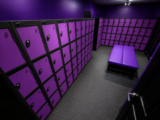Purple lockers lined up in a gym changing area, with a bench in the centre.